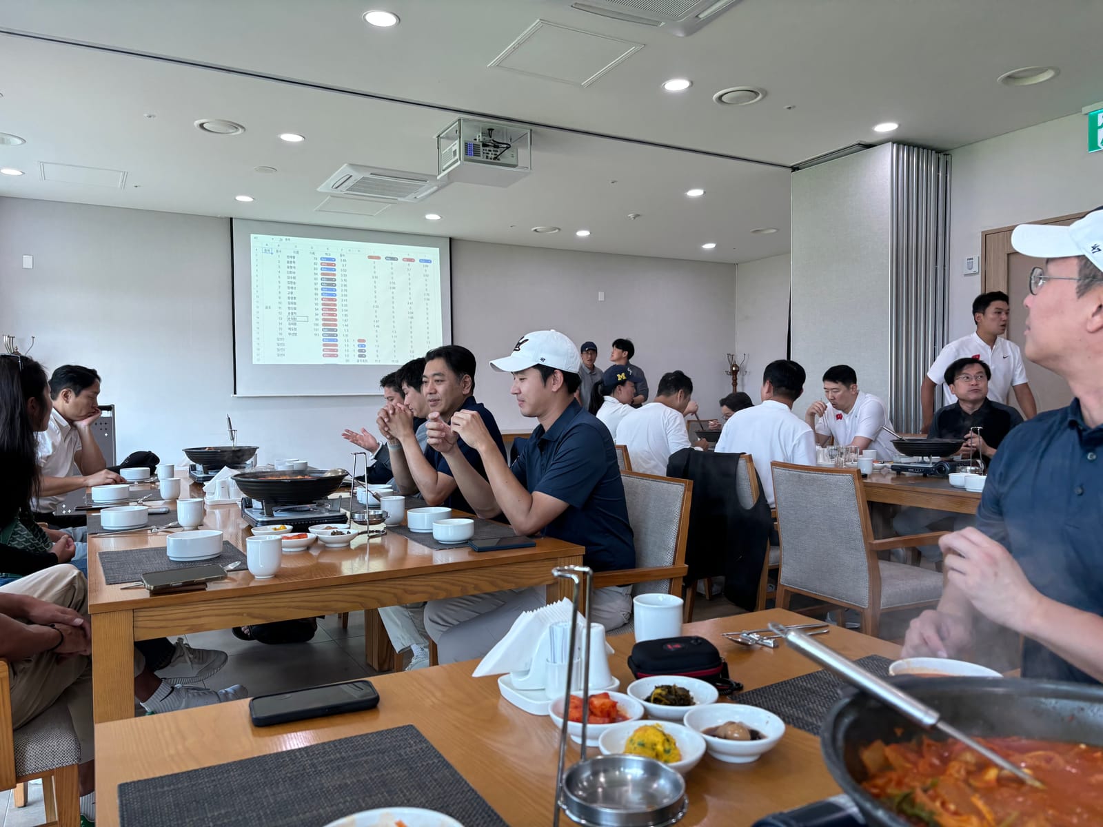 Alumni at lunch with the results on screen