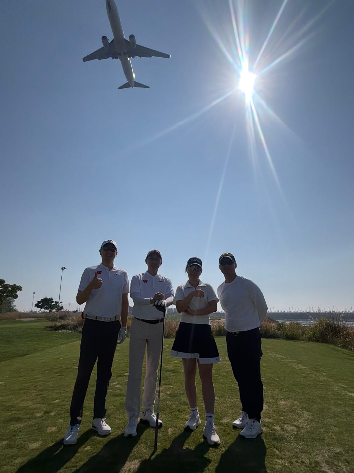 Golfers under a plane passing overhead